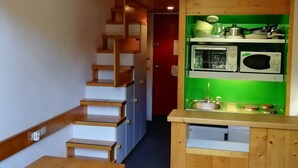 A wooden staircase leading to a kitchen with a green wall, a microwave, and a sink. - Ski-in duplex for 5 in Charmettoger with WIFI (Les Arcs 1800)