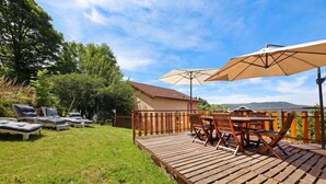 A wooden deck with outdoor furniture, a table, and an umbrella. - Homerez - Spacious House in Gérardmer (Gérardmer)