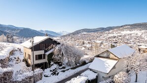 A snow-covered town with buildings, a clear sky, and mountains in the background. - Homerez - Spacious House in Gérardmer (Gérardmer)