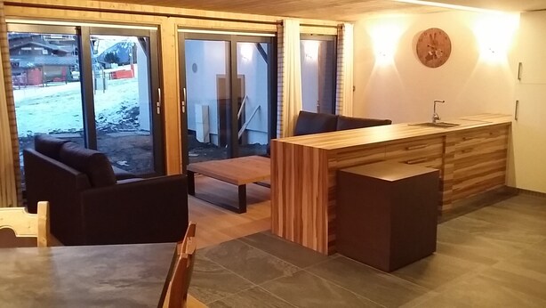 Una cocina moderna con encimera de madera, un fregadero y una zona de comedor con banco y sillas.