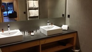 Un baño moderno con dos lavamanos, un espejo grande y un perchero para toallas.