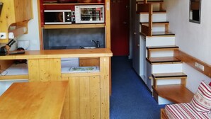A compact kitchen with a microwave, toaster, and sink. A wooden counter and a small table are visible. - Duplex 2 Rooms - 5 Pers, Charmettoger Arc 1800, Pets Allowed (Les Arcs 1800)