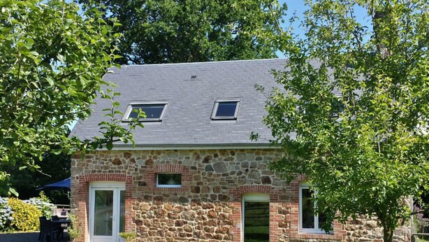 A stone house with a sloped roof, a front door, and a small porch area.