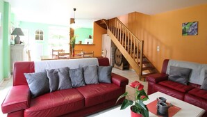 A living room with red leather sofas, a white coffee table, and a staircase.