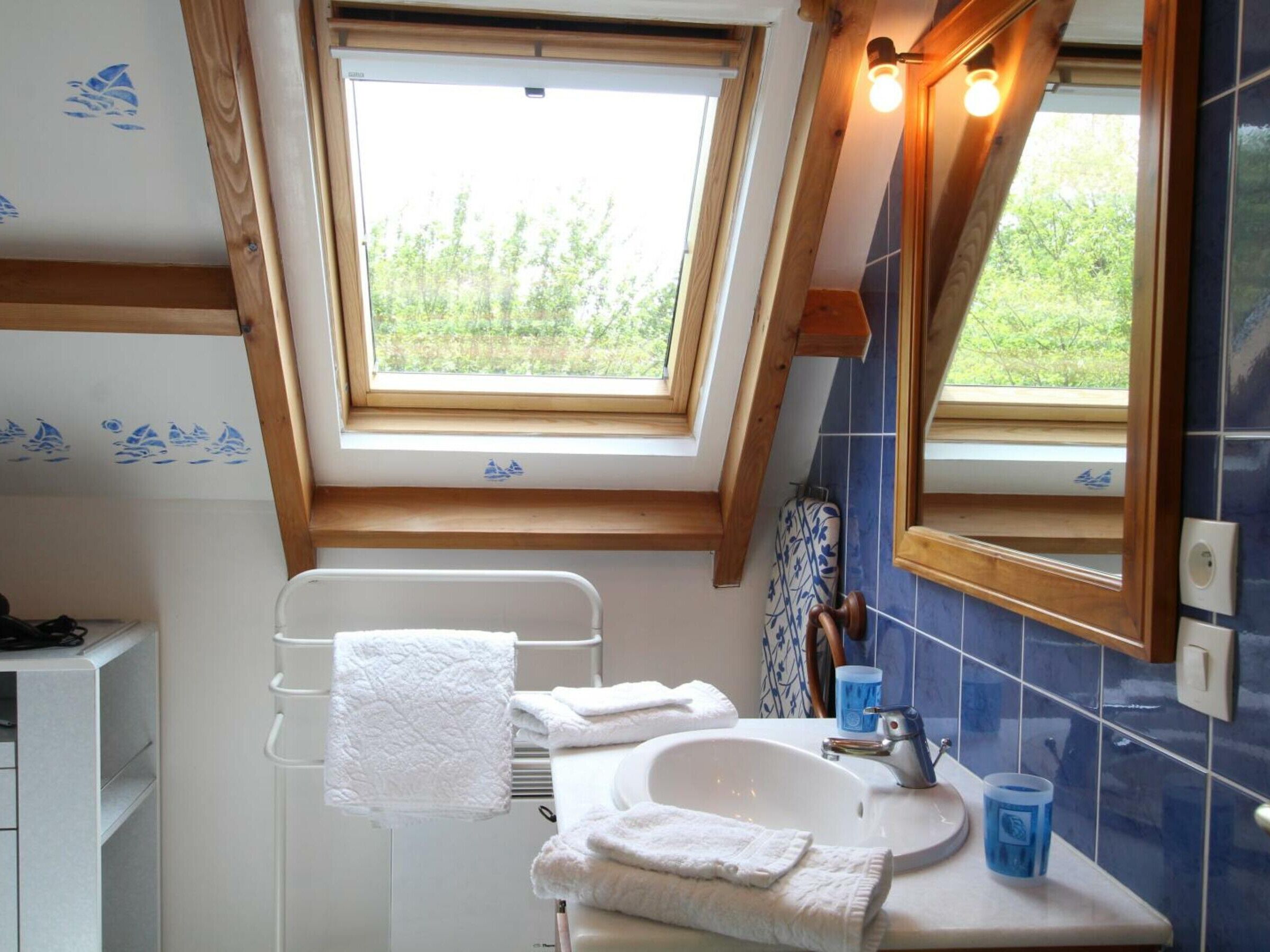 A bathroom with a skylight, a white sink, and a mirror.
