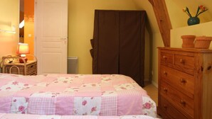Une chambre à coucher avec un lit, une commode en bois, une porte et une lampe.