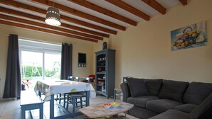 Un salon avec un canapé, une table à manger et des chaises, une bibliothèque et un tableau accroché au mur.