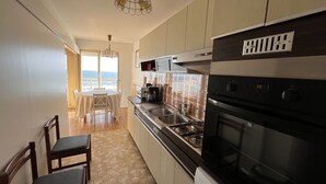 Een compacte keuken met een gasfornuis, oven en een eethoek met uitzicht.