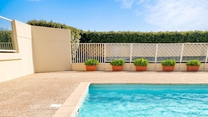 A rectangular swimming pool with clear blue water, surrounded by a pebble border and a tiled deck.