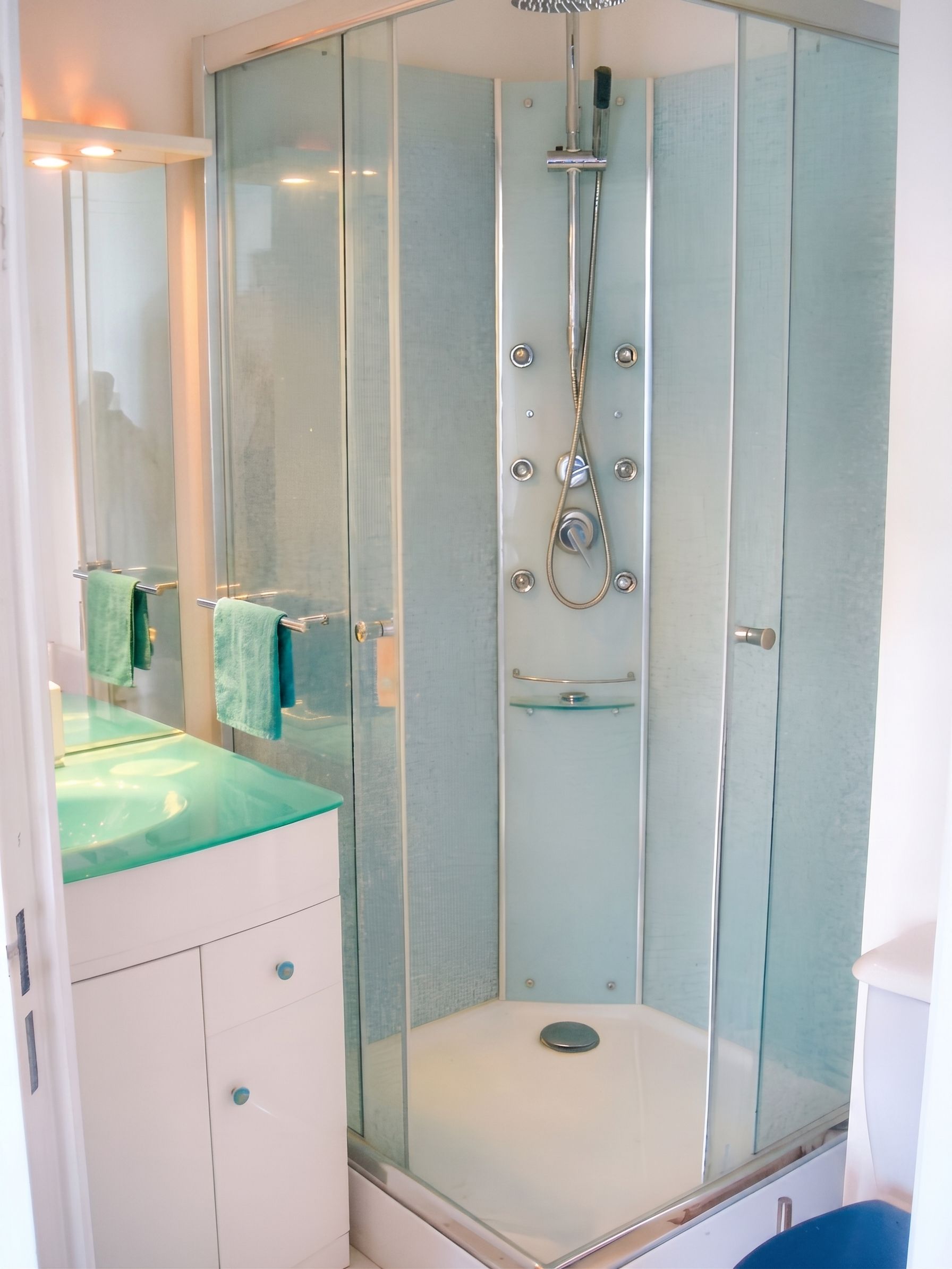 A modern bathroom with a glass-enclosed shower, a vanity with a green countertop, and a mirror.