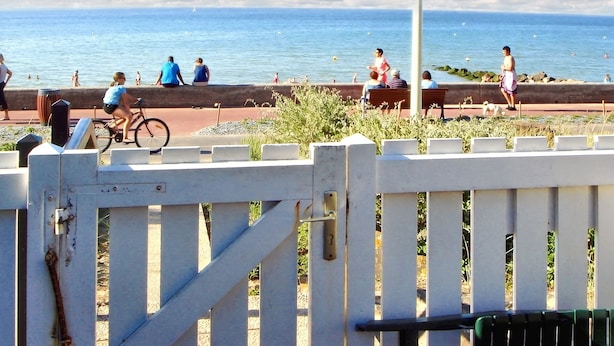 A coastal walkway with benches, a bicycle, and a view of the sea.