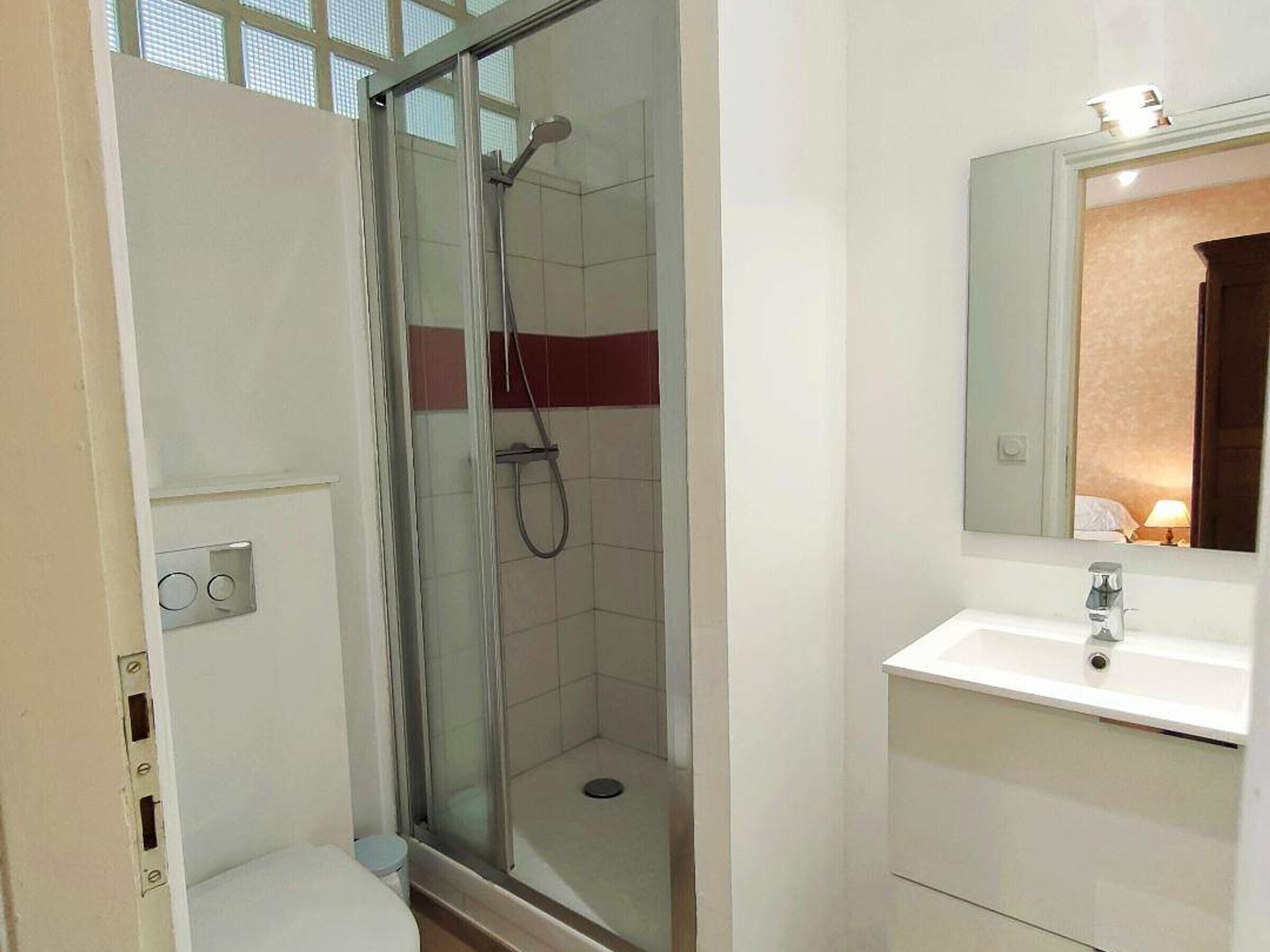 Une salle de bain moderne avec une douche à parois de verre, un lavabo blanc et un miroir au-dessus.