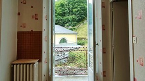 A narrow hallway with a radiator and a door leading to a balcony with a view of a house and a hill. - 2-room apartment, 4 beds in Cauterets near thermal baths (Cauterets)