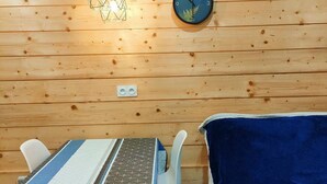 A wooden interior with a bed, a table with chairs, a wall clock, and a geometric light fixture. - 2-room apartment, 4 beds in Cauterets near thermal baths (Cauterets)