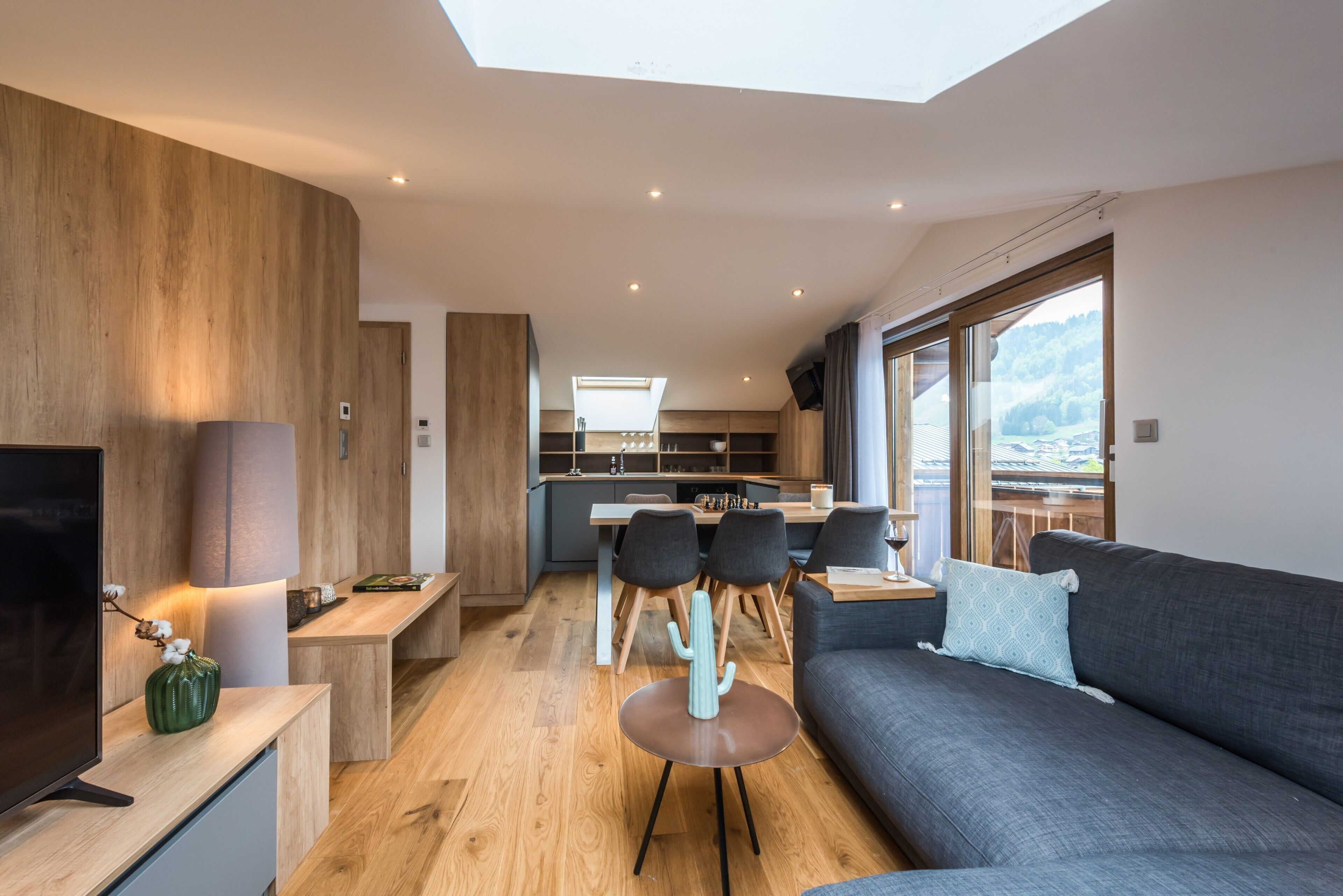 Un salon moderne avec un canapé, un téléviseur et un coin repas comprenant des chaises et une table.