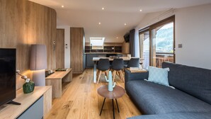 Un salon moderne avec un canapé, un téléviseur et un coin repas comprenant des chaises et une table.