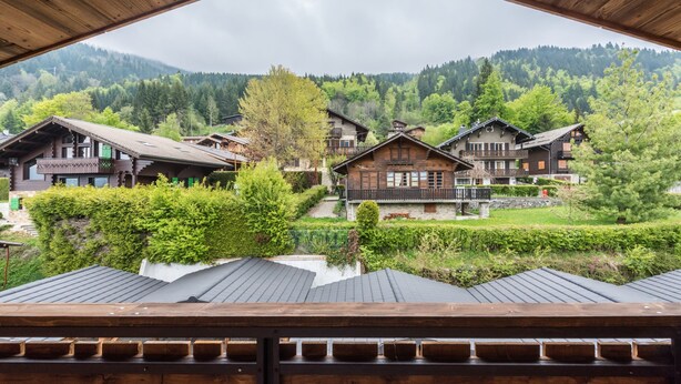 Une cabane en bois offrant une vue sur un village et des montagnes boisées.