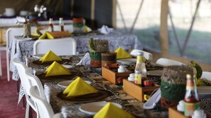 A dining table set with yellow napkins, wooden blocks, and bottles. - Serengeti Wildebeest Camp (Serengeti)