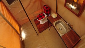 A compact bathroom with a toilet, sink, and a mirror. - Serengeti Wildebeest Camp (Serengeti)