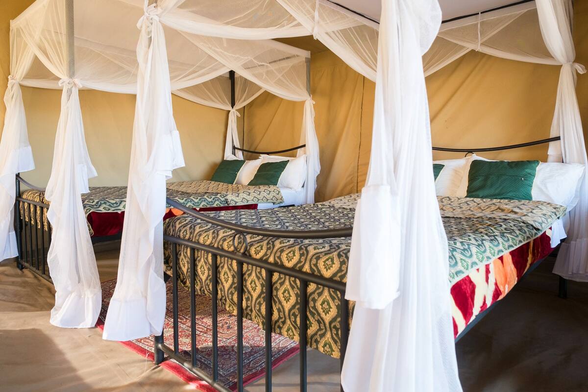 A room with four beds, each with a canopy bedspread and a patterned bedspread.
