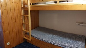 Un letto a castello con una scala in legno, un materasso a pois e una presa di corrente.