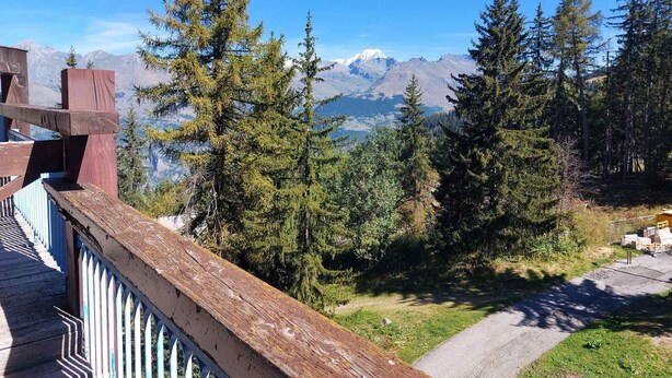 Un terrazzo in legno con vista su un paesaggio montano.