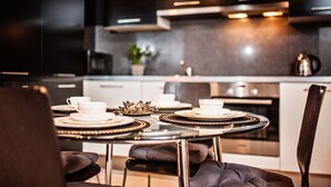 A modern kitchen with a dining table set for four, equipped with white plates and cups. - Apartamenty Homely Place Centrum (Poznan)