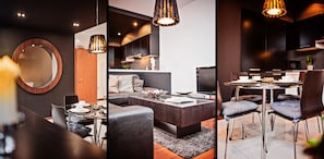 A modern living space with a round mirror, dark-toned furniture, and a dining area with a glass table and metal chairs.