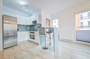A modern kitchen with white cabinets, stainless steel appliances, and a bar area with stools.