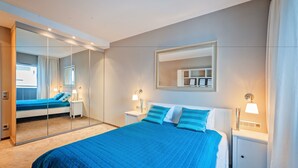 A bedroom with a large bed, two bedside tables with lamps, a mirror, and a wardrobe. - Apartamenty Homely Place Centrum (Poznan)