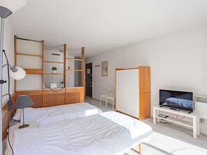 A modern hotel room with two beds, a desk, a television, and a wardrobe. - Central Studio with Pool Access and Sea View in Biarritz (Biarritz)