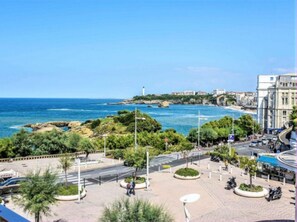 A coastal urban area with a clear view of the sea, a lighthouse, and buildings.