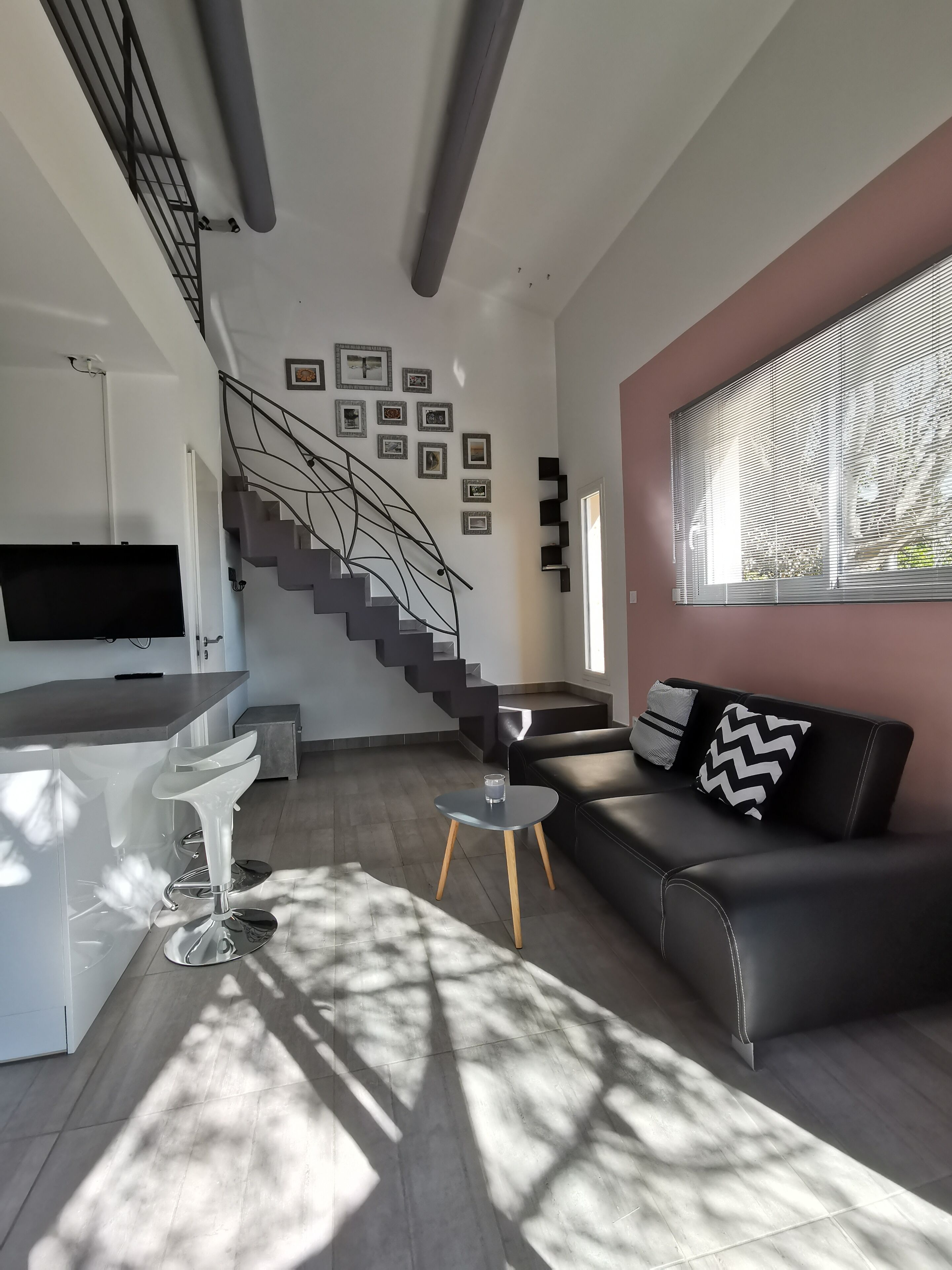 Un salon moderne doté d’un escalier, d’un téléviseur à écran plat, d’un coin repas et d’un canapé agrémenté de coussins décoratifs.
