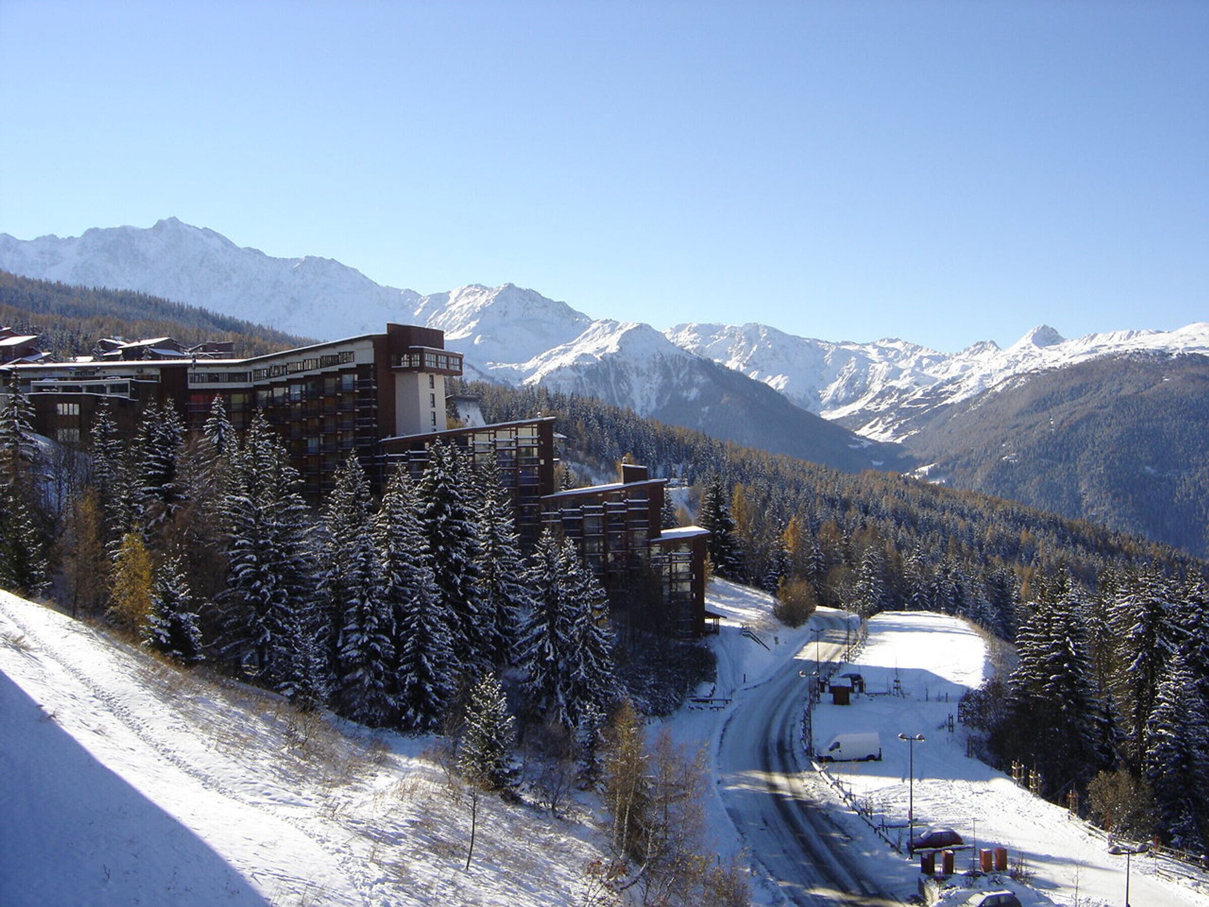 A modern hotel with multiple floors, surrounded by snow-covered trees and mountains.