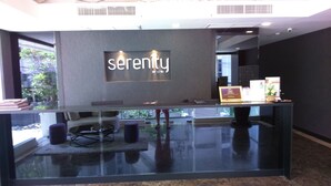 A reception area with a glass counter, a sofa, and a chair. - Serenity Wongamat Pattaya Studio (Pattaya)