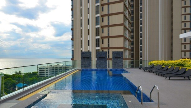 A rooftop pool with a view of the sea, surrounded by high-rise buildings. - Serenity Wongamat Pattaya Studio (Pattaya)