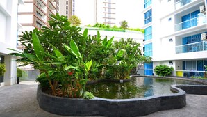 A courtyard with a central water feature surrounded by lush greenery and modern buildings. - Serenity Wongamat Pattaya Studio (Pattaya)