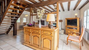 A spacious living area with a wooden staircase, a wooden cabinet with drawers, a television, and a chair. - Homerez - House in Bangor (Bangor)