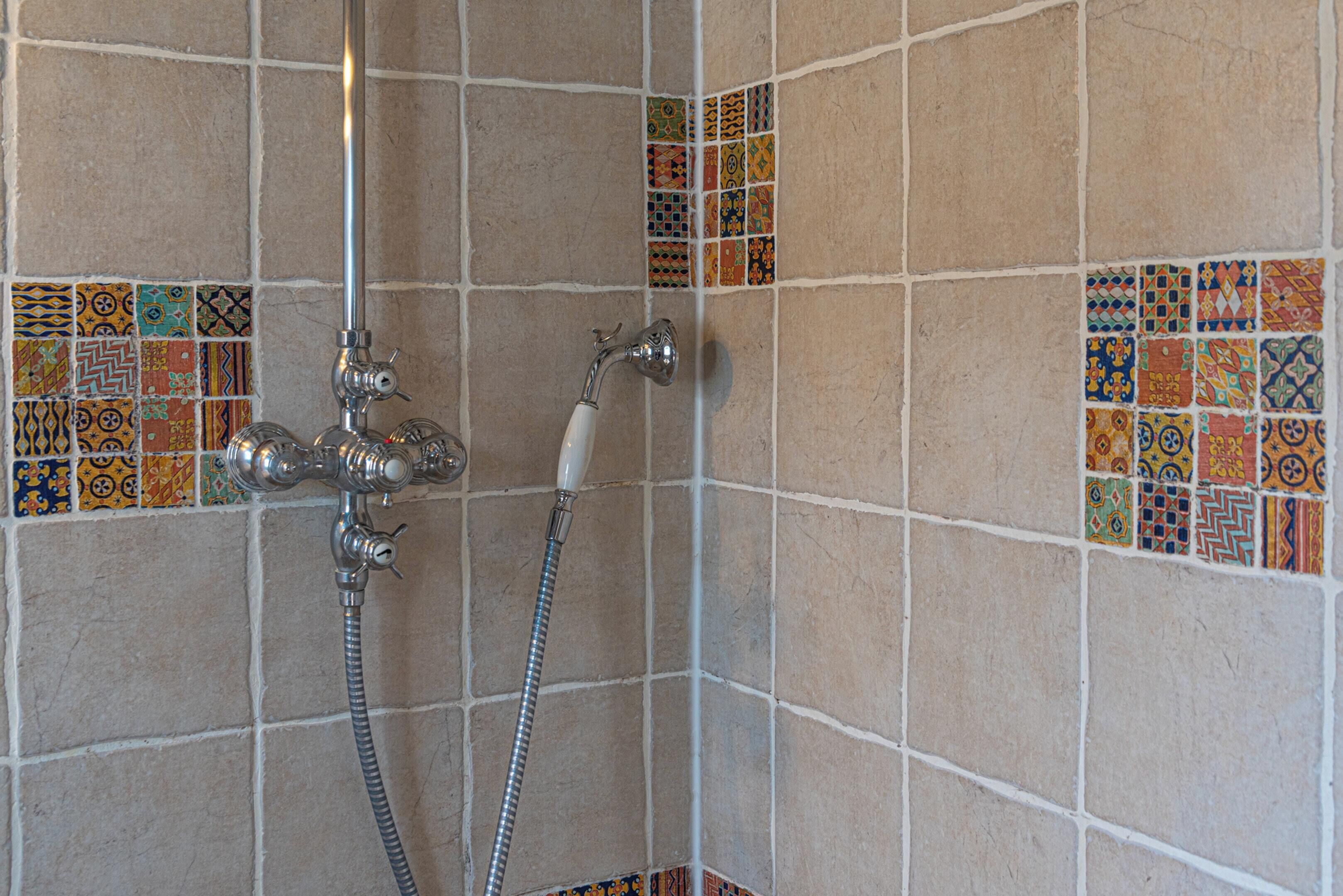 Zona de ducha con pared de azulejos y cabezal de ducha.