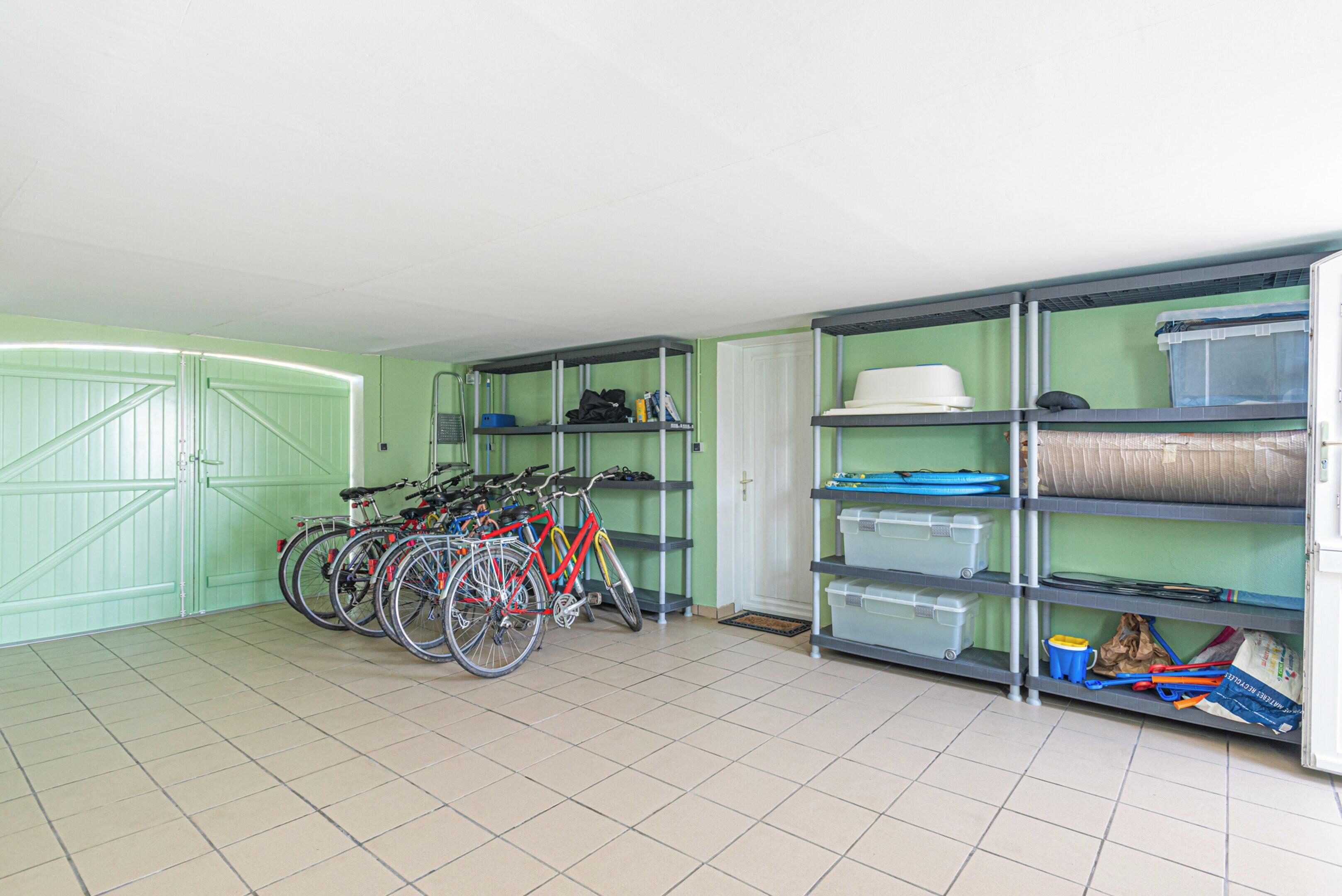 Une pièce de rangement contenant des vélos, des étagères et des bacs de rangement.