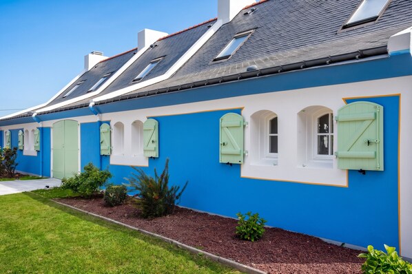 A row of houses with blue walls and green shutters, each with a small garden in front. - Homerez - House in Bangor (Bangor)