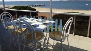 A table set for dining with chairs, overlooking a beach and the sea. - 3-Bed Apt in Central Arcachon, Sea View, Parking, Pets Allowed, Wifi (Arcachon)