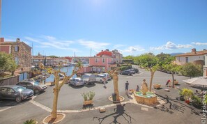 A marina with boats, a parking area with cars, and buildings with red and white facades.