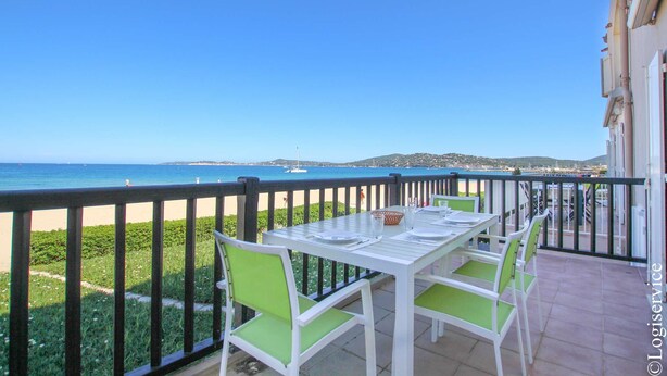 A balcony with a table and chairs, overlooking a beach and the sea. - On the beach flat for 4 persons with sea view (PORT-GRIMAUD)