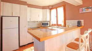 A compact kitchen with white cabinets, a Bosch refrigerator, a microwave, and a wooden island with bar stools. - On the beach flat for 4 persons with sea view (PORT-GRIMAUD)