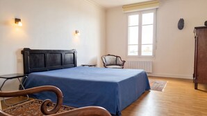 Una camera da letto con un letto, una sedia, una finestra e un termosifone.