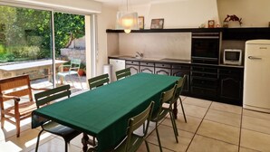 Una cucina con tavolo da pranzo, sedie, frigorifero e lavello.