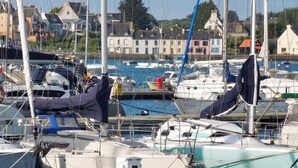 A marina with boats docked, a clear sky, and buildings in the background. - Homerez - House in Camaret sur Mer (Camaret sur mer)