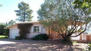 Ein eingeschossiges Haus mit Ziegeldach, Garage und einer kleinen Veranda.