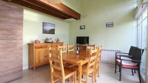 Un comedor con una mesa y sillas de madera, un televisor y una ventana con persianas.